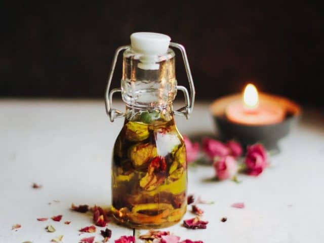 Massageöl aus Rosenblüten, Orangenschalen und Bio-Avocadoöl von FRANZ & CO. auf einem Tisch in einer kleinen Bügelflache