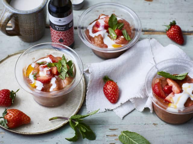 Rhabarber-Erdbeer-Grütze in Desserschälchen auf einem Tisch, zubereitet mit Würzöl Olive & Chili von FRANZ & CO.