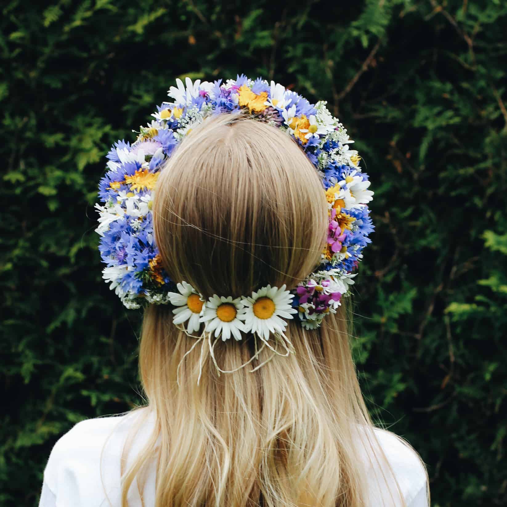 Fertiger Kranz aus bunten Wildblumen auf dem Kopf eines Mädchens.